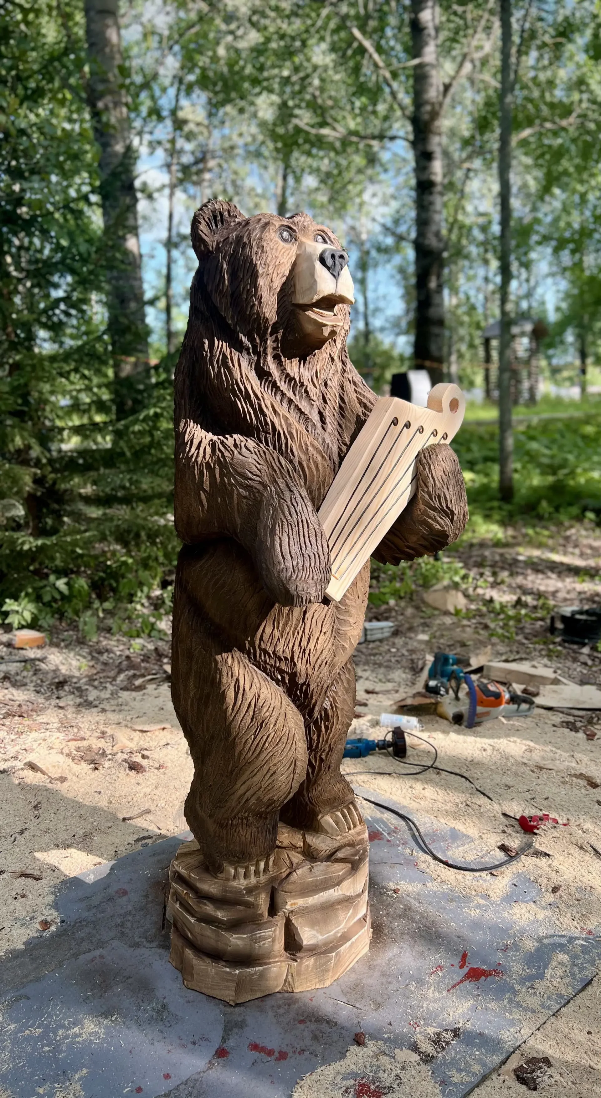 Moottorisahalla tehty puuveistos, jossa karhu pitelee kanteletta kädessään.