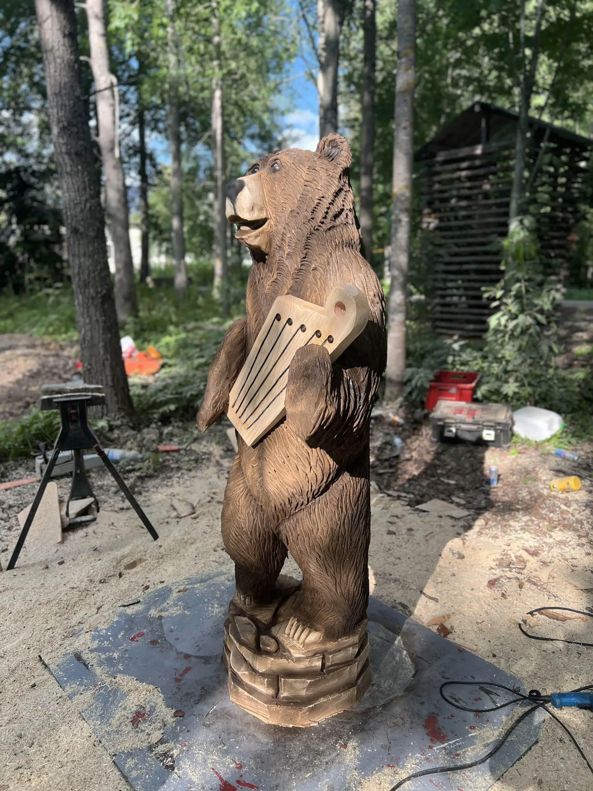 Moottorisahalla tehty puuveistos, jossa karhu pitelee kanteletta kädessään.